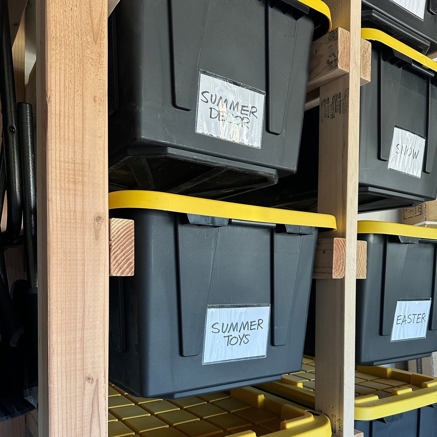 Stack of black storage boxes with labels stored on a tote rack.