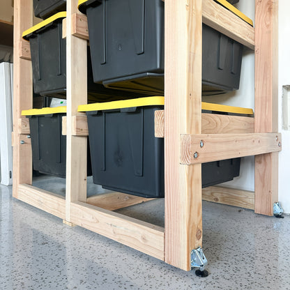 Stack of black storage bins on a wooden pallet with yellow straps.